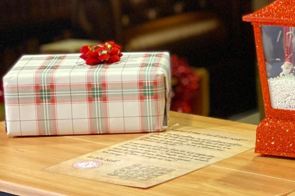Animation CSE de Noël, gros plan sur un cadeau en papier tartan à nœud rouge posé dans le bureau du Père Noël