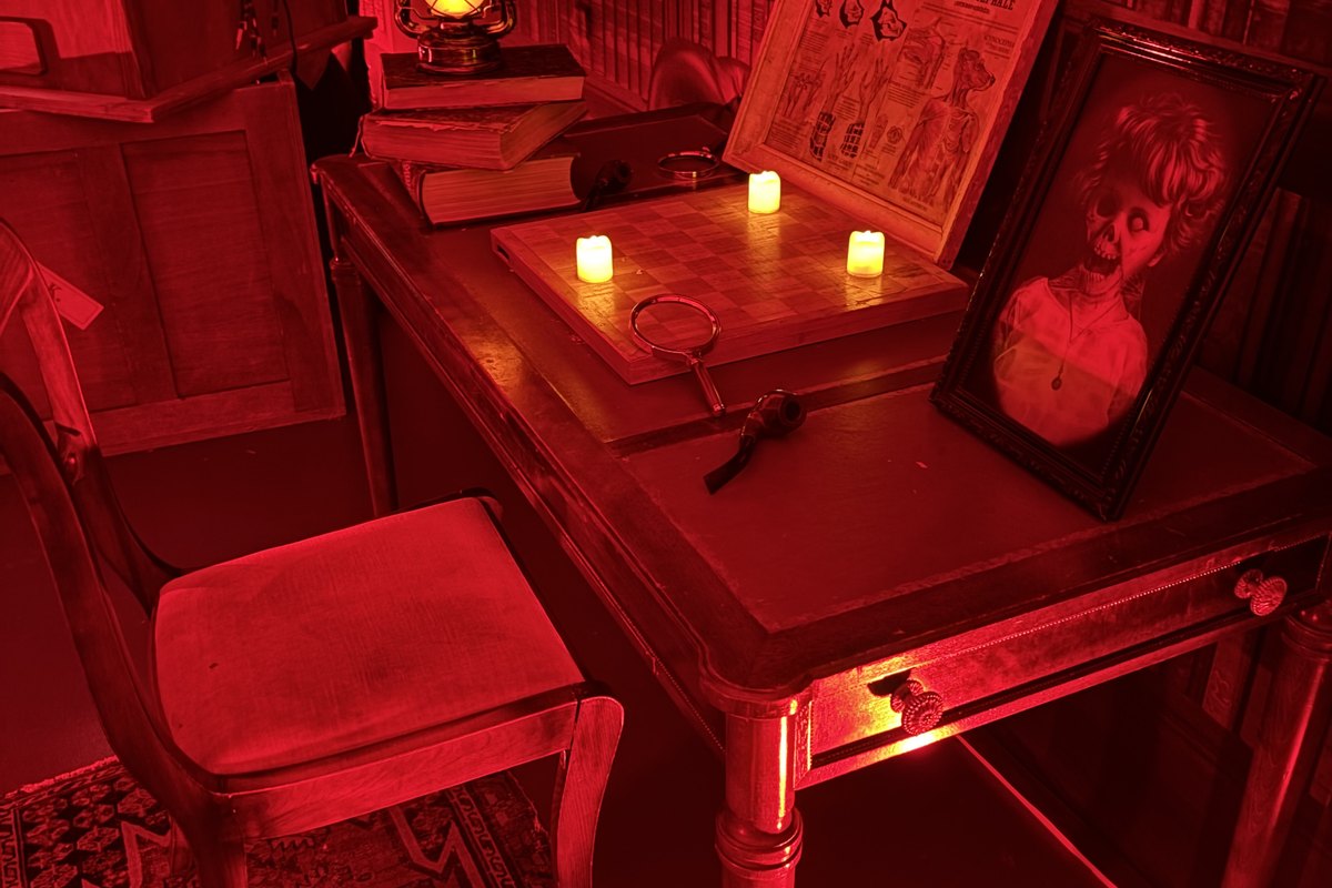 Animation escape game mobile frisson, le bureau du tueur avec loupe, bougies et portrait encadré, en entreprise