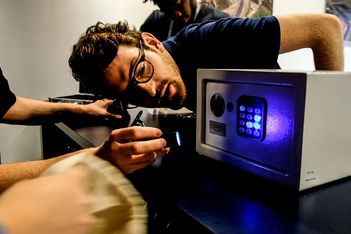 Escape game nomade en entreprise, équipe qui inspecte le coffre du Colis Mystérieux à la lampe UV