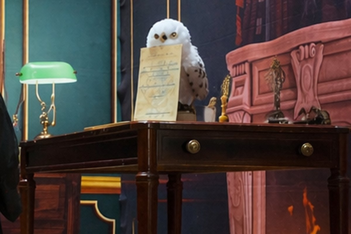 Escape game mobile sur le thème de la magie, chouette blanche posée sur le bureau du magicien à côté d'un parchemin et d'une lampe verte