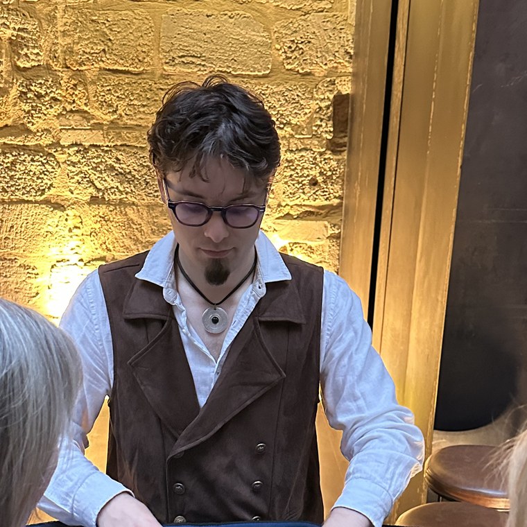 Le Croupier, un des convives suspects du gala, en gilet de soirée à la table de jeu