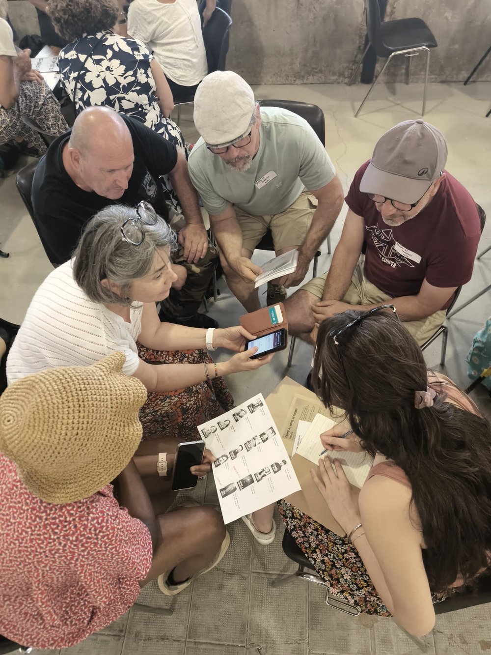 Un groupe de participants penché sur des documents et un téléphone, en pleine déduction